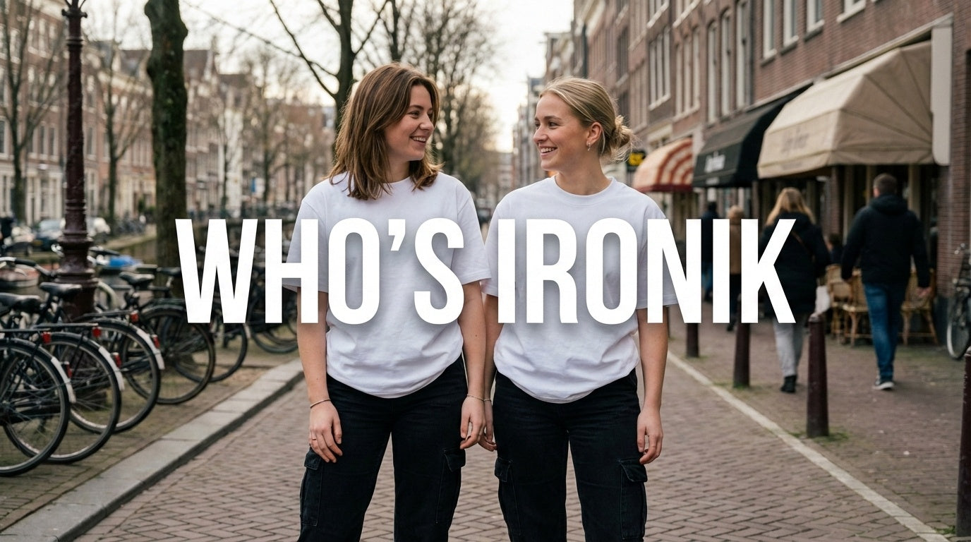 Two women laughing wearing white Ironik t-shirts and black cargo pants on a cobblestone street with text "WHO'S IRONIK".